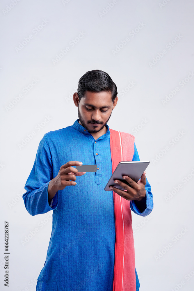 Young indian farmer using smartphone and bank card on white background.