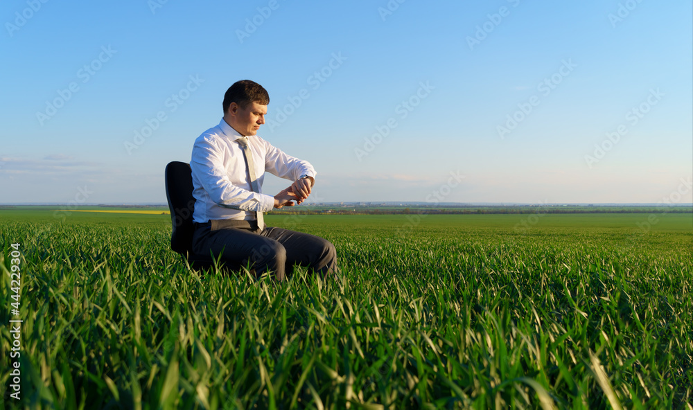 businessman sits in an office chair in a field and rests, freelance and business concept, green grass and blue sky as background businessman sits in an office chair in a field and rests, freelance and business concept, green grass and blue sky as background