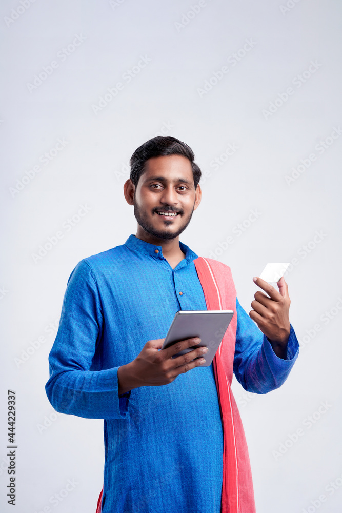 Young indian farmer using smartphone and bank card on white background. Young indian farmer using smartphone and bank card on white background.