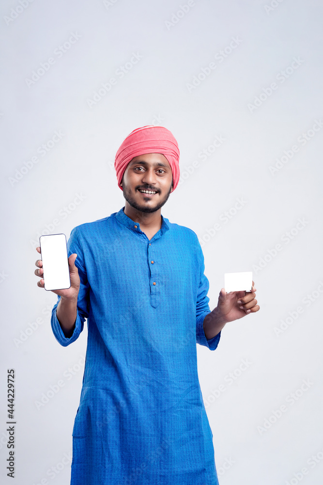 Young indian farmer showing card and smartphone on white background. Young indian farmer showing card and smartphone on white background.