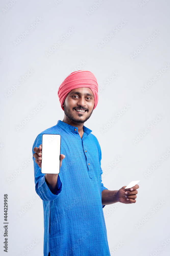 Young indian farmer showing card and smartphone on white background. Young indian farmer showing card and smartphone on white background.