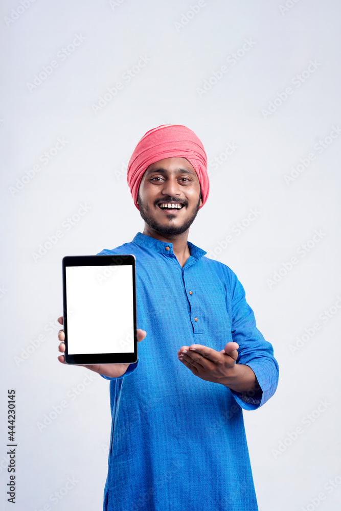Young indian man in traditional wear and showing tablet over white background. Young indian man in traditional wear and showing tablet over white background.