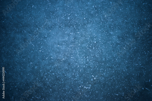 An icy dark background with white patches of frost and frozen round bubbles