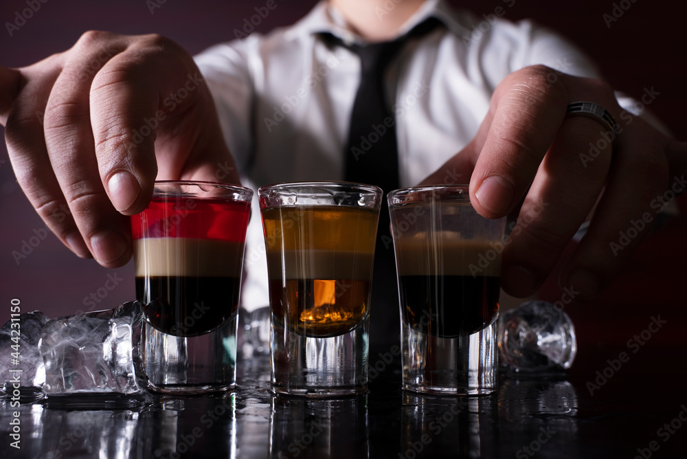 Barman preparing cocktail shots at the bar counter. Barman mixing drinks at the night club..