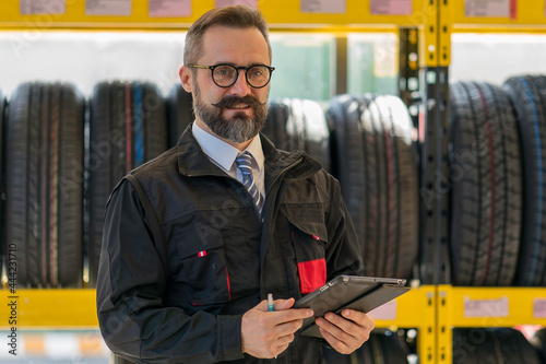 Portrait of senior man mechanic in tires shop services. Good service and professional tires shop concept.