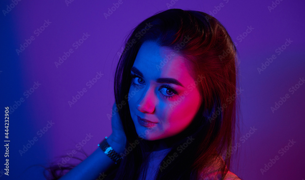 Portrait of fashionable young woman that standing in the studio with neon light