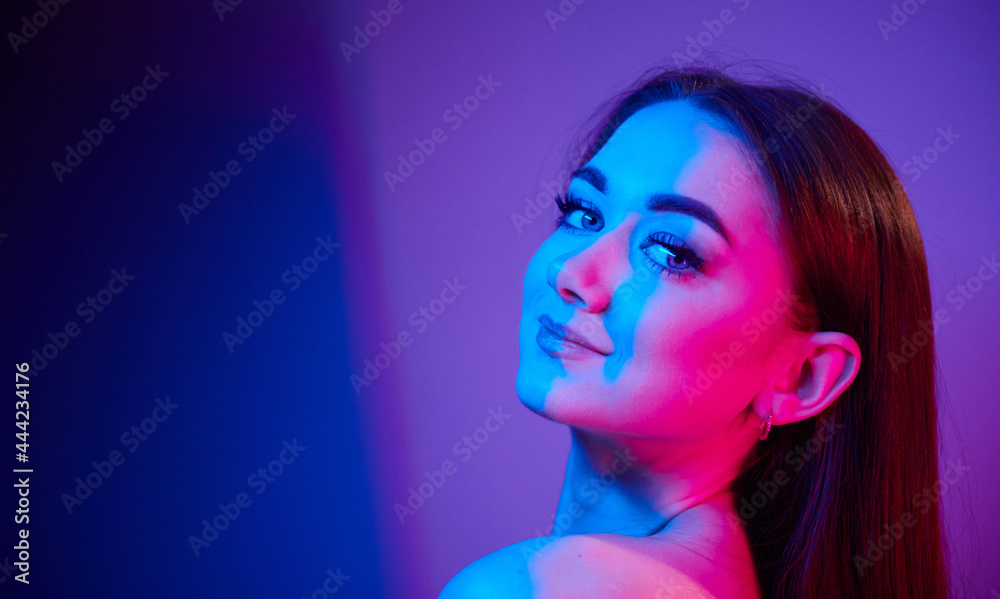 Close up view. Fashionable young woman standing in the studio with neon light Close up view. Fashionable young woman standing in the studio with neon light