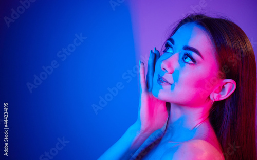 Close up view. Fashionable young woman standing in the studio with neon light
