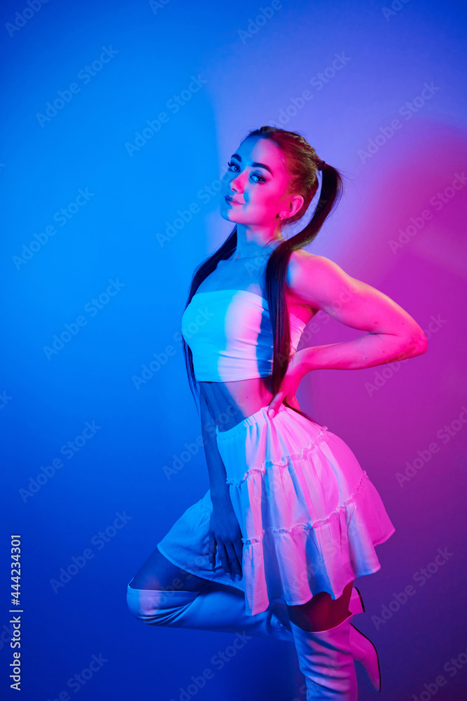 In skirt. Fashionable young woman standing in the studio with neon light In skirt. Fashionable young woman standing in the studio with neon light
