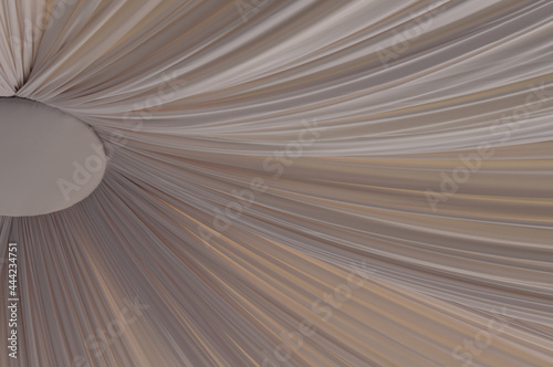 A blurred image of a ceiling draped with a beige powdery fabric.