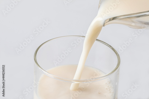 Pouring fresh white milk from bottle into a glass. Healthy food concept.