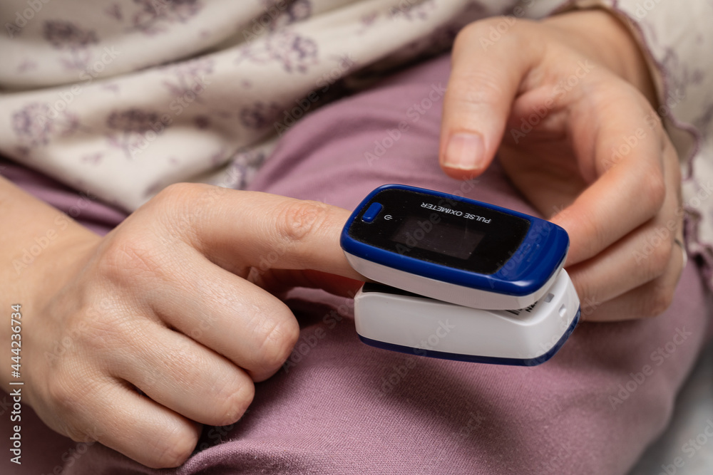 Pulse oximeter used to measure pulse rate and oxygen levels. Female hand with heart rate monitor Pulse oximeter used to measure pulse rate and oxygen levels. Female hand with heart rate monitor
