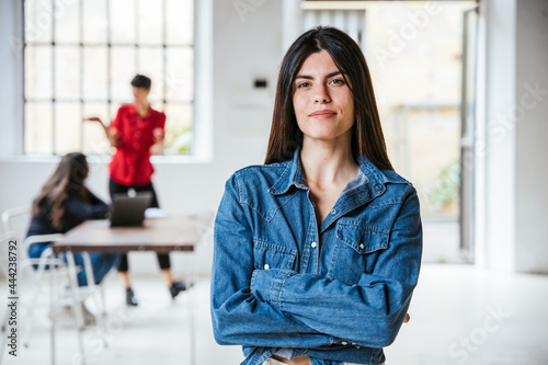 Foto Portrait of a young female businesswoman with arms folded in her new office, beh