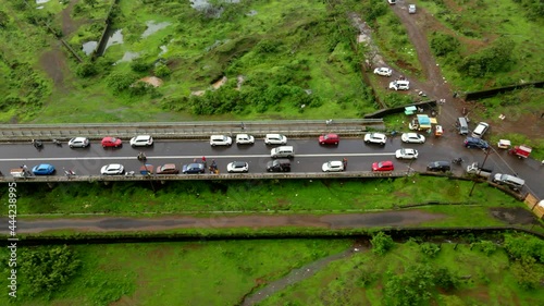 lonavla city hill station dron shot following car top view birds eye view in rainy day  city inova passing thrugh traffic off road Bhushi Dam city . photo