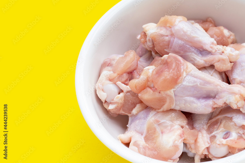 Fresh raw chicken wings (wingstick) in white bowl on yellow background. Fresh raw chicken wings (wingstick) in white bowl on yellow background.