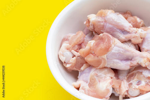 Fresh raw chicken wings (wingstick) in white bowl on yellow background.