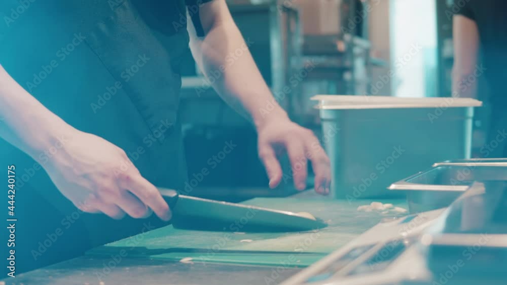 A cook is chopping onion on the cutting board A cook is chopping onion on the cutting board