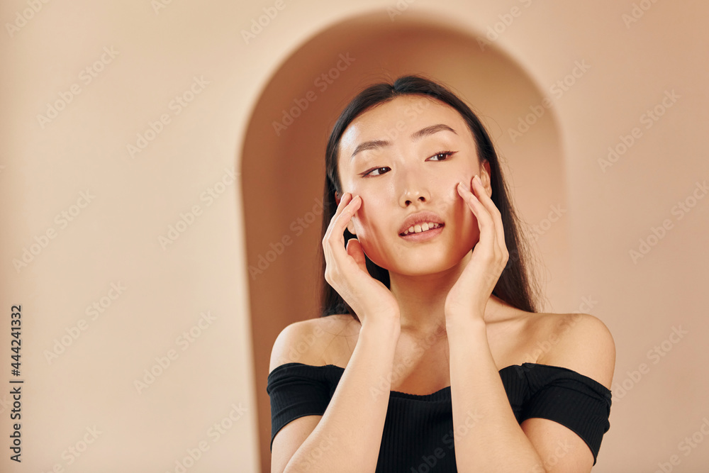 Posing for a camera. Young serious asian woman standing indoors Posing for a camera. Young serious asian woman standing indoors