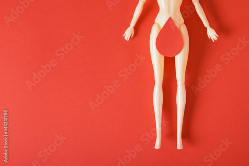 doll with a paper drop of blood on the thighs, feminism art, women's health and gnecology concept, menstruation photo