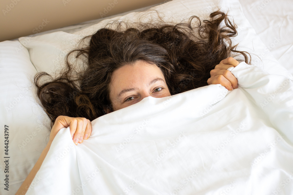 Happy brunette woman lying in bed hugging soft white pillow. Smiling looking in distance, enjoying fresh soft bedding and orthopedic mattress in bedroom. Relaxing, resting, lazy weekend morning. Happy brunette woman lying in bed hugging soft white pillow. Smiling looking in distance, enjoying fresh soft bedding and orthopedic mattress in bedroom. Relaxing, resting, lazy weekend morning.
