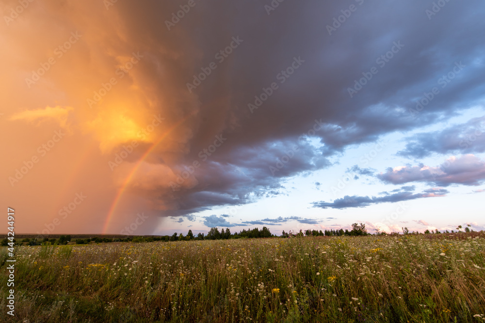 Storm clouds with a rainbow before sunset