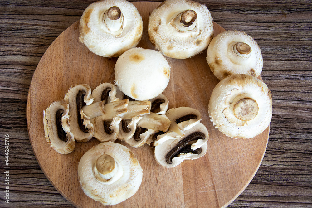 Champignons top view. Champignon mushrooms lie on a wooden cutting board. Chopped edible mushrooms. Champignons top view. Champignon mushrooms lie on a wooden cutting board. Chopped edible mushrooms.