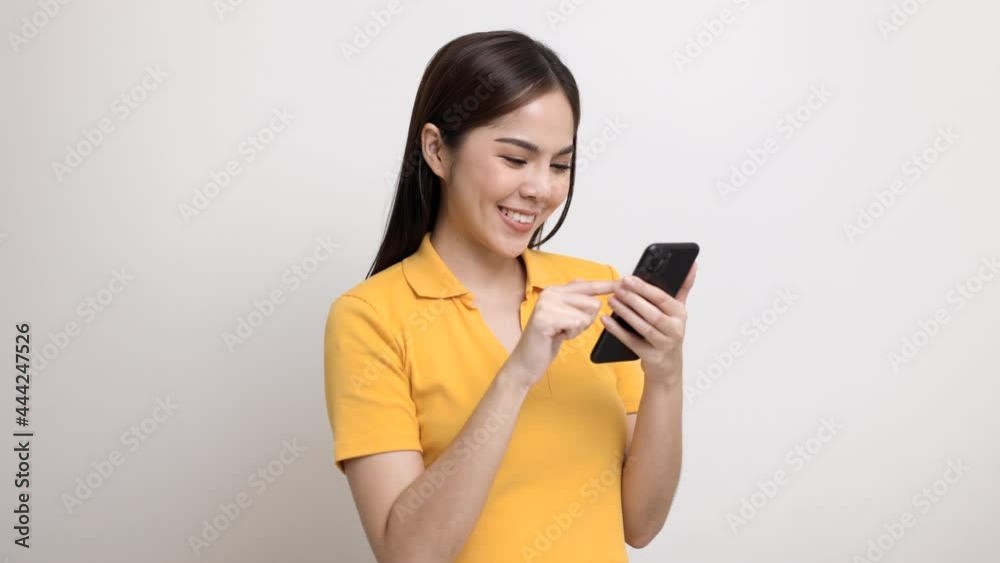 Pretty young asian woman using smartphone standing on isolated white background. She texting on cell phone. Pretty young asian woman using smartphone standing on isolated white background. She texting on cell phone.