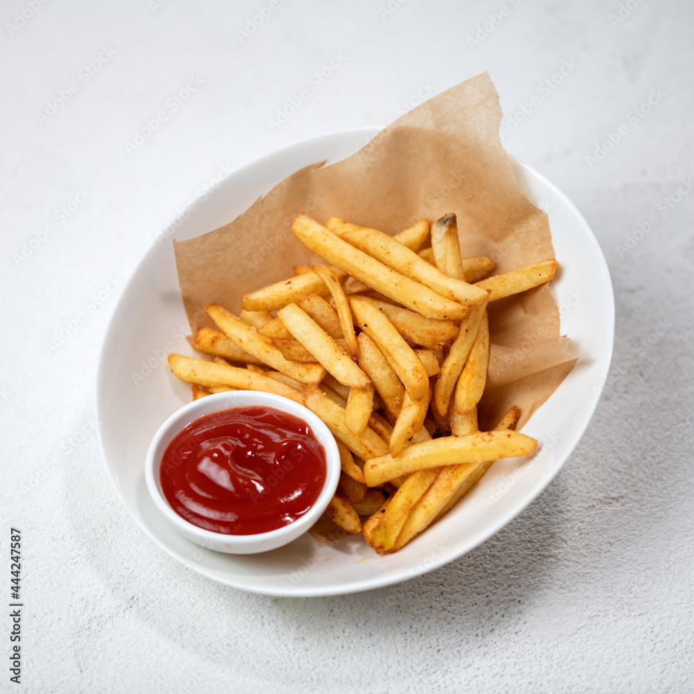 Fried potatoes with tomato sauce, fries with ketchup. Food plate isolated on white background.