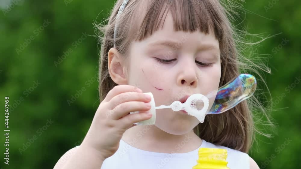 A cute little girl blowing on a dandelion in a spring park. Happy kid having fun outdoors. A cute little girl blowing on a dandelion in a spring park. Happy kid having fun outdoors.
