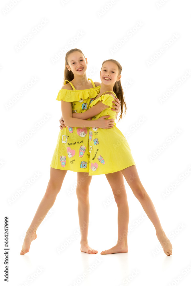 Two Happy Teen Girls Sisters in Yellow Dresses Hugging and Smili Two Happy Teen Girls Sisters in Yellow Dresses Hugging and Smili