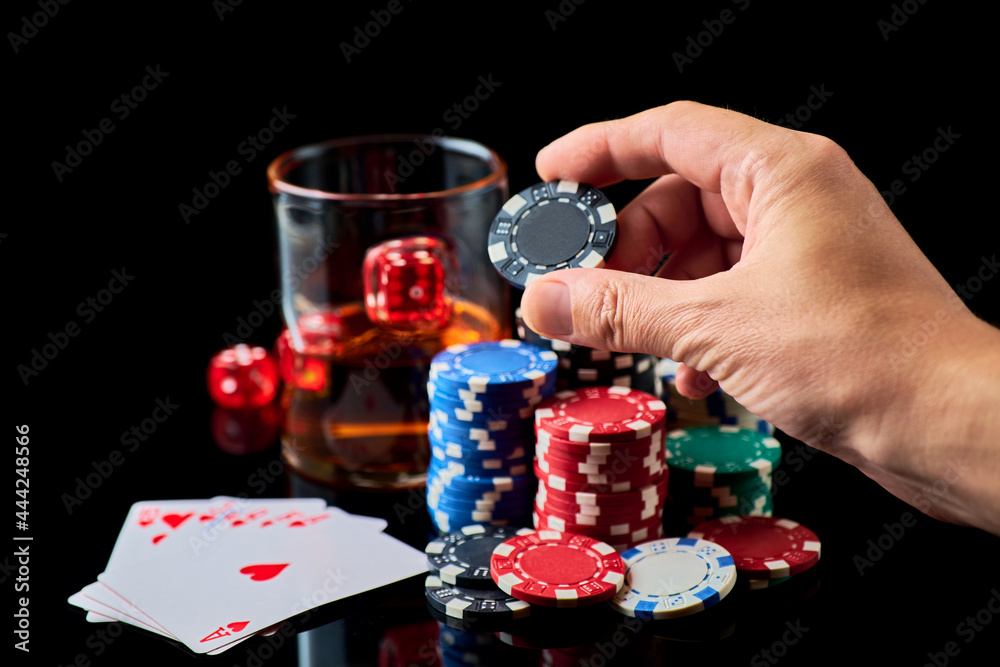 Casino chips, playing cards, glass of whiskey and dices on dark reflective background