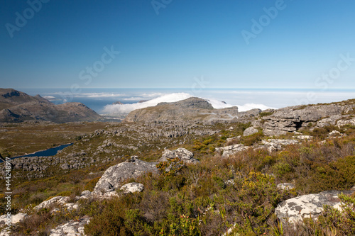 Panoramic view from top of Table Mountain to Hout Bay, Cape Town, South Africa with upcoming clouds.