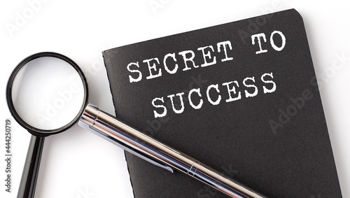 SECRET TO SUCCESS - business concept, magnifier with white text message on black notebook