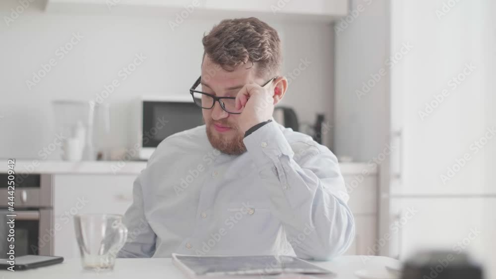 A young man in glasses and stylish light clothes communicates over a homemade breakfast