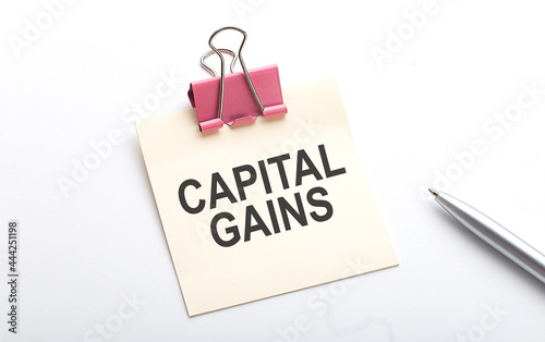 CAPITAL GAINS text on sticker with pen on the white background