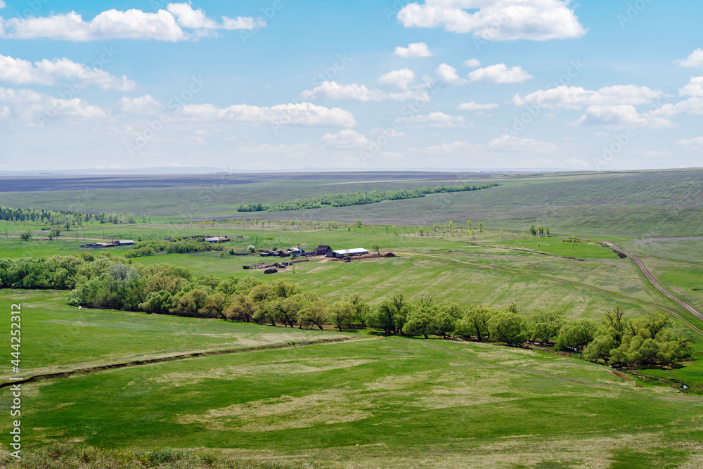 Spring rural landscape with a farm, fields and a country road. Photo taken near the village of Voskresenovka, Orenburg region, Russia
