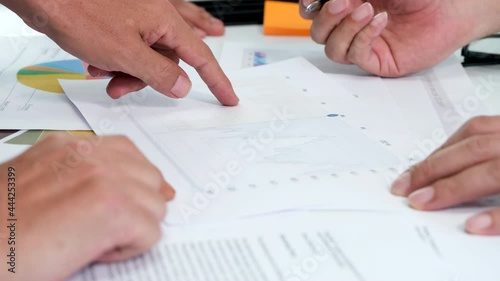 Close up hands of business people checks financial graphs at desk in office. Colleagues looking at documents with diagrams and examining documents. Concept of working together, brainstorming. 