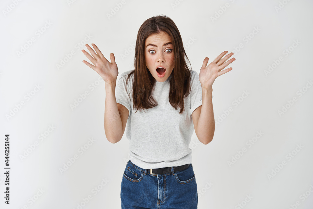 Happy young woman screaming of surprise and joy, looking excited down at promo banner, standing over white background Happy young woman screaming of surprise and joy, looking excited down at promo banner, standing over white background
