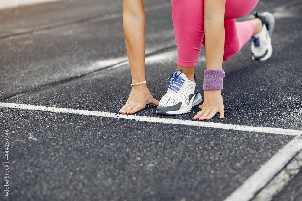 Sports girl in a pink uniform runs at the stadium