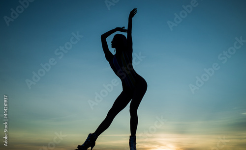Free dance of woman ballet dancer silhouetted in dusk on evening sky, freedom