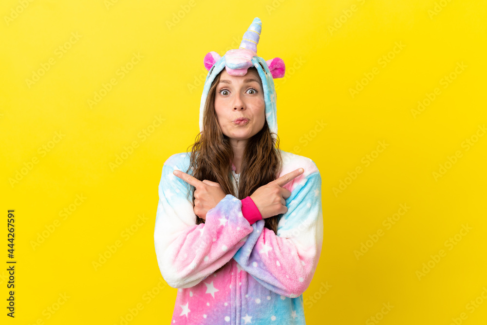 Girl with unicorn pajamas over isolated background pointing to the laterals having doubts