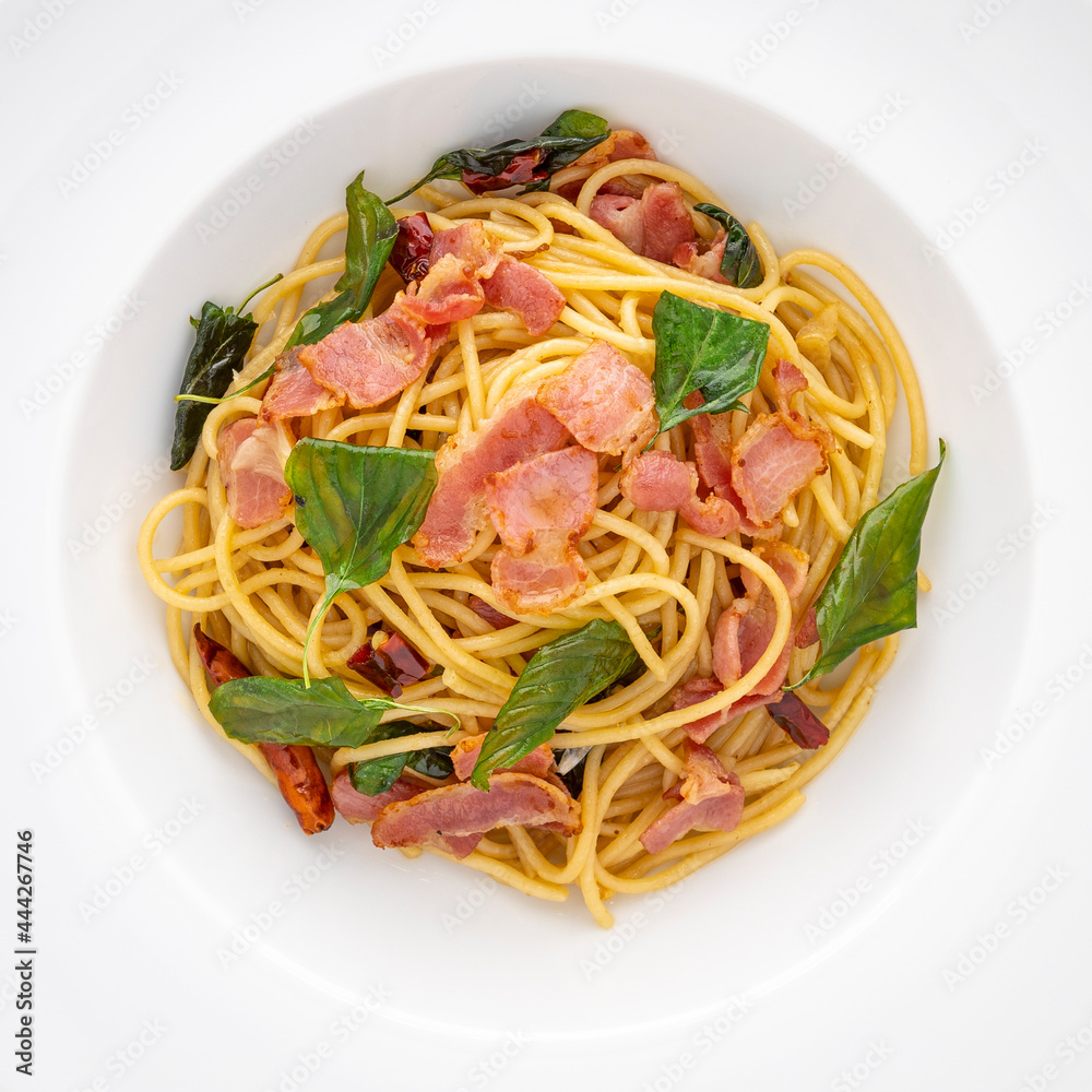 top view shot of Spaghetti Pasta with Dried Chilli, Garlic, Sweet Basil and Bacon in white ceramic plate texture background, square ratio top view shot of Spaghetti Pasta with Dried Chilli, Garlic, Sweet Basil and Bacon in white ceramic plate texture background, square ratio