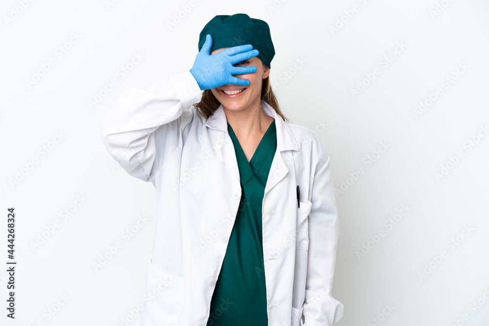 Surgeon caucasian woman in green uniform isolated on white background covering eyes by hands and smiling Surgeon caucasian woman in green uniform isolated on white background covering eyes by hands and smiling