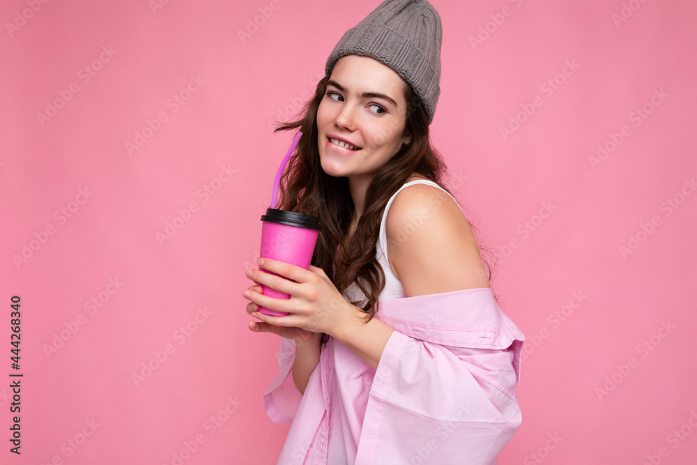Photo of attractive young happy smiling brunette woman wearing everyday stylish clothes isolated over colourful background wall holding paper cup for cutout drinking tea looking to the side Photo of attractive young happy smiling brunette woman wearing everyday stylish clothes isolated over colourful background wall holding paper cup for cutout drinking tea looking to the side