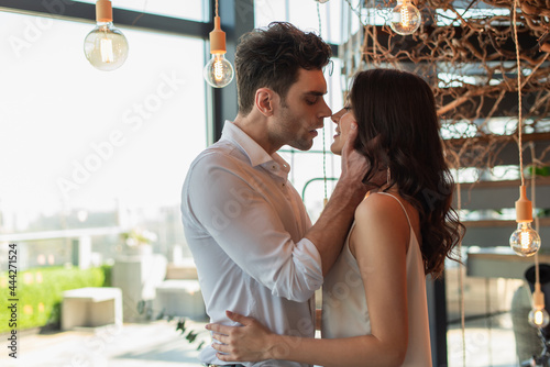 side view of man hugging young brunette woman in restaurant