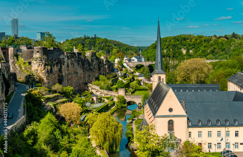 Panoramic view of Luxembourg-City with Neumünster abbey, medieval houses in the lower city, trees, and Kirchberg skyline in the background