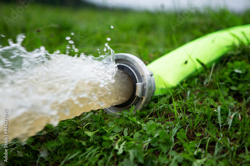 Schlauch und spritzendes Wasser. Feuerwehr pumpt Wasser ab