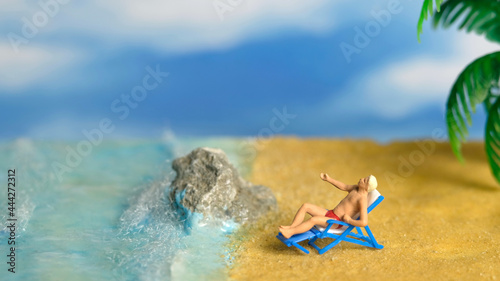 Fototapeta Naklejka Na Ścianę i Meble -  Miniature people toy figure photography. A Men relaxing on beach chair when daylight at seaside.