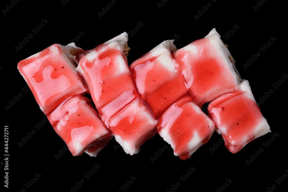 Sweet dessert in the form of rolls poured with syrup. Isolated on a black background, close-up