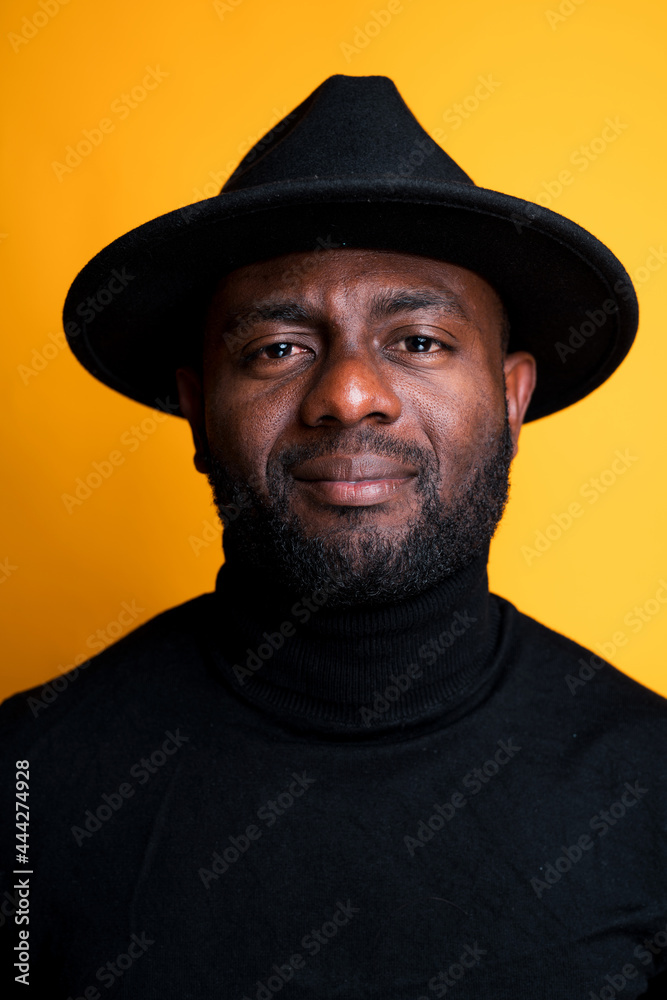 Portrait of an African American man in a black turtleneck and hat. Isolated on yellow background Portrait of an African American man in a black turtleneck and hat. Isolated on yellow background